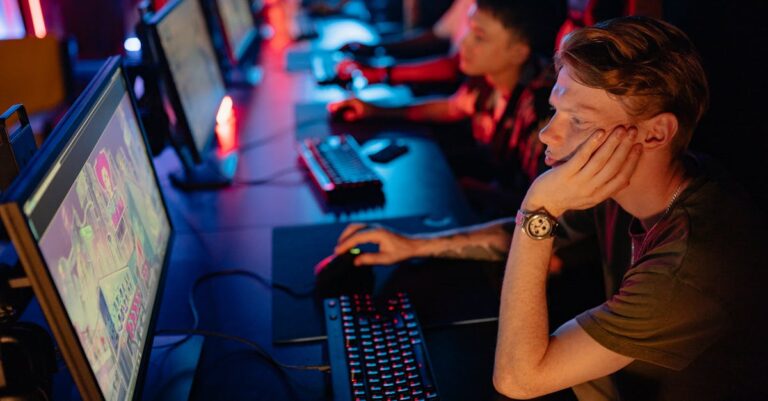 Gamers intensely focused on a computer game during an online esport competition in a dimly lit arena.